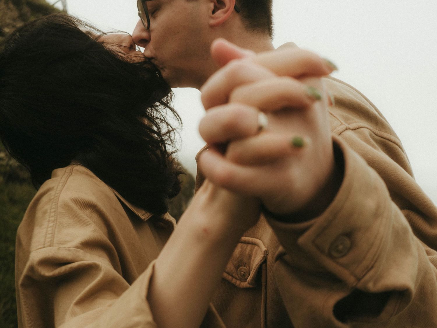 slightly blurry photograph of a couple sharing a kiss, there's a lot of movement and you can see their hands extended towards the camera