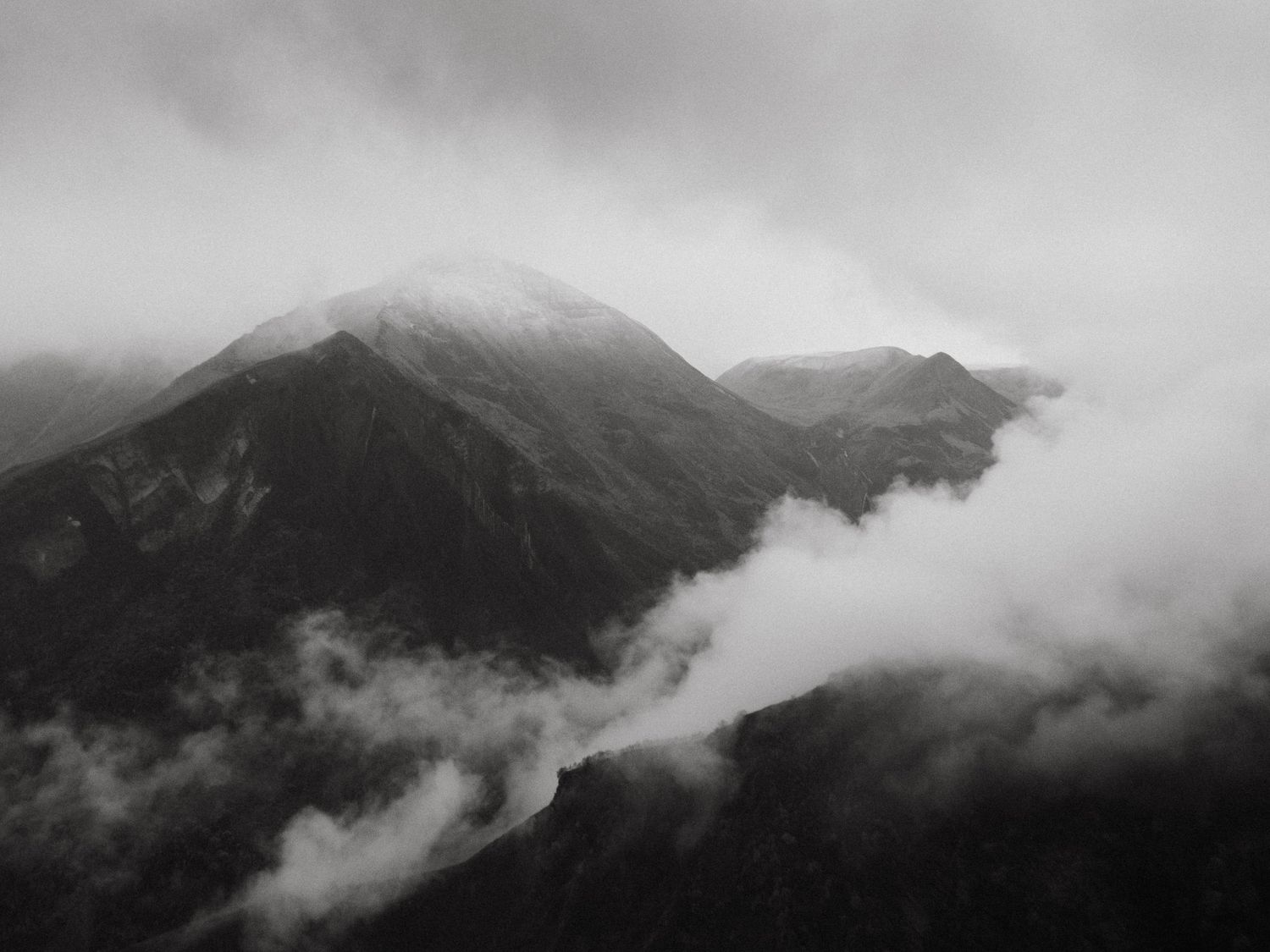 Black and white photograph of mountain front in clouds, taken from the Russian-georgian friendship monument in Georgia