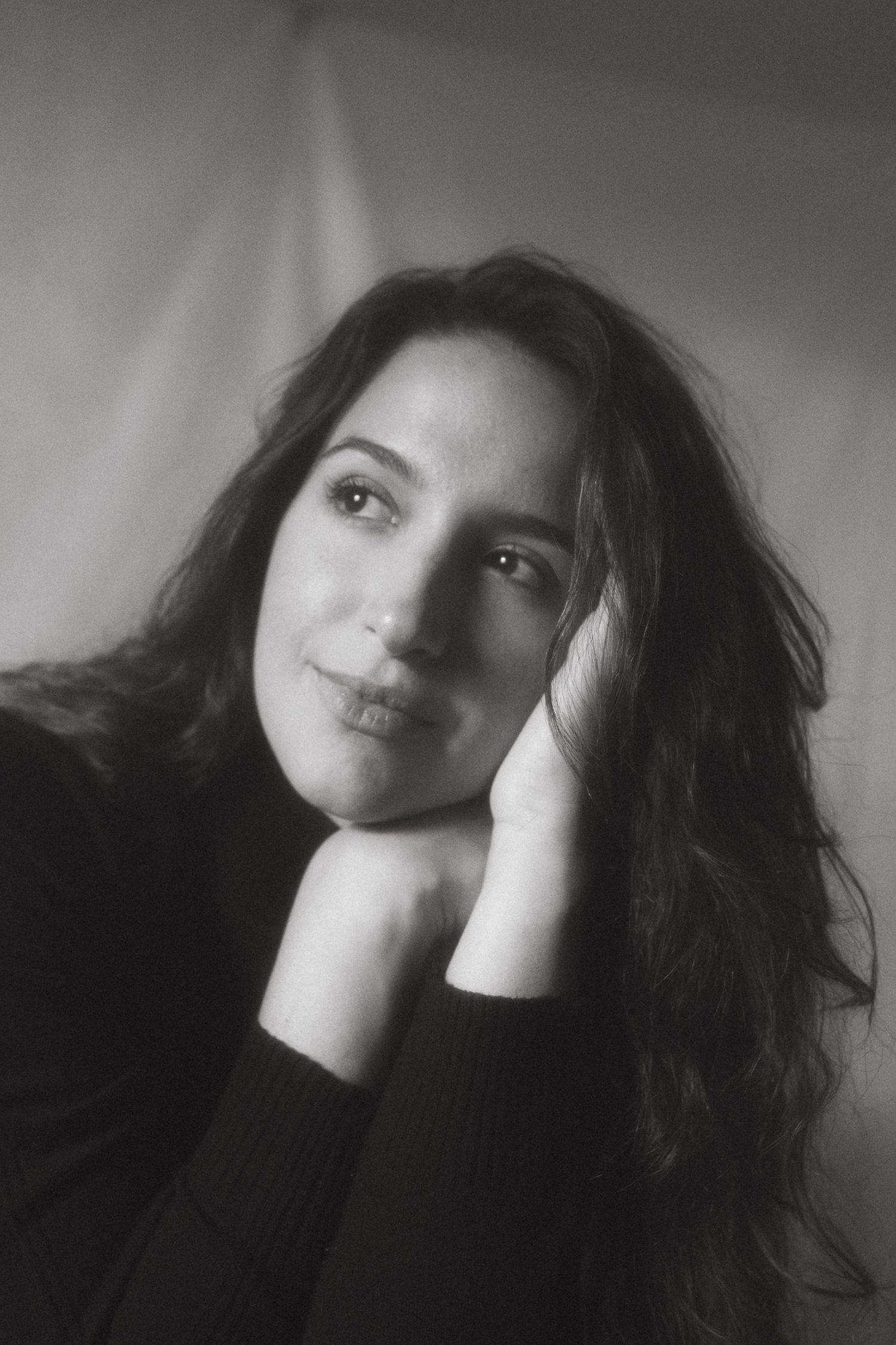 Black and white photograph of a dark haired model in a studio setting, soft contrast.