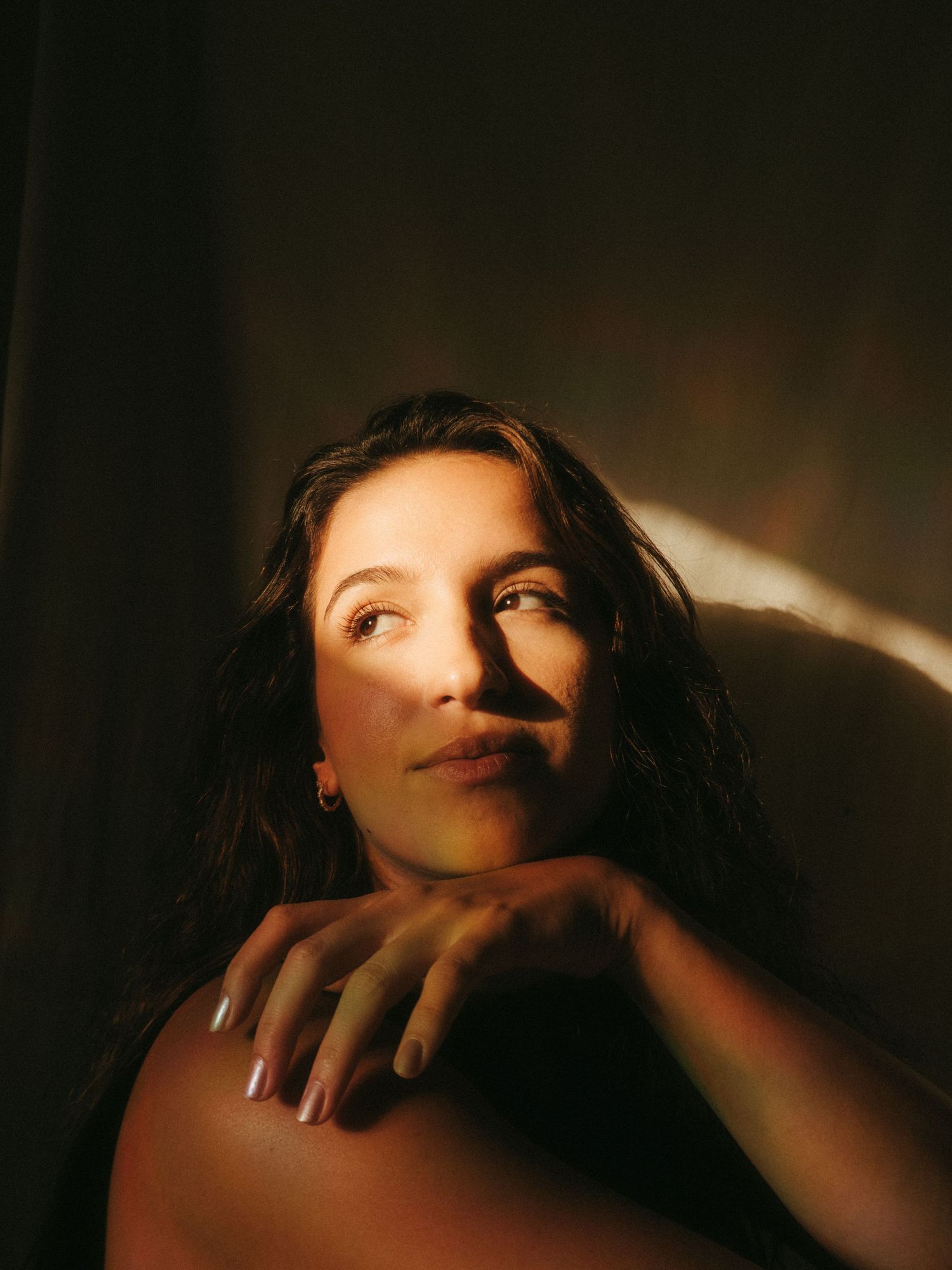 photograph of a dark haired model in a studio setting, soft contrast.