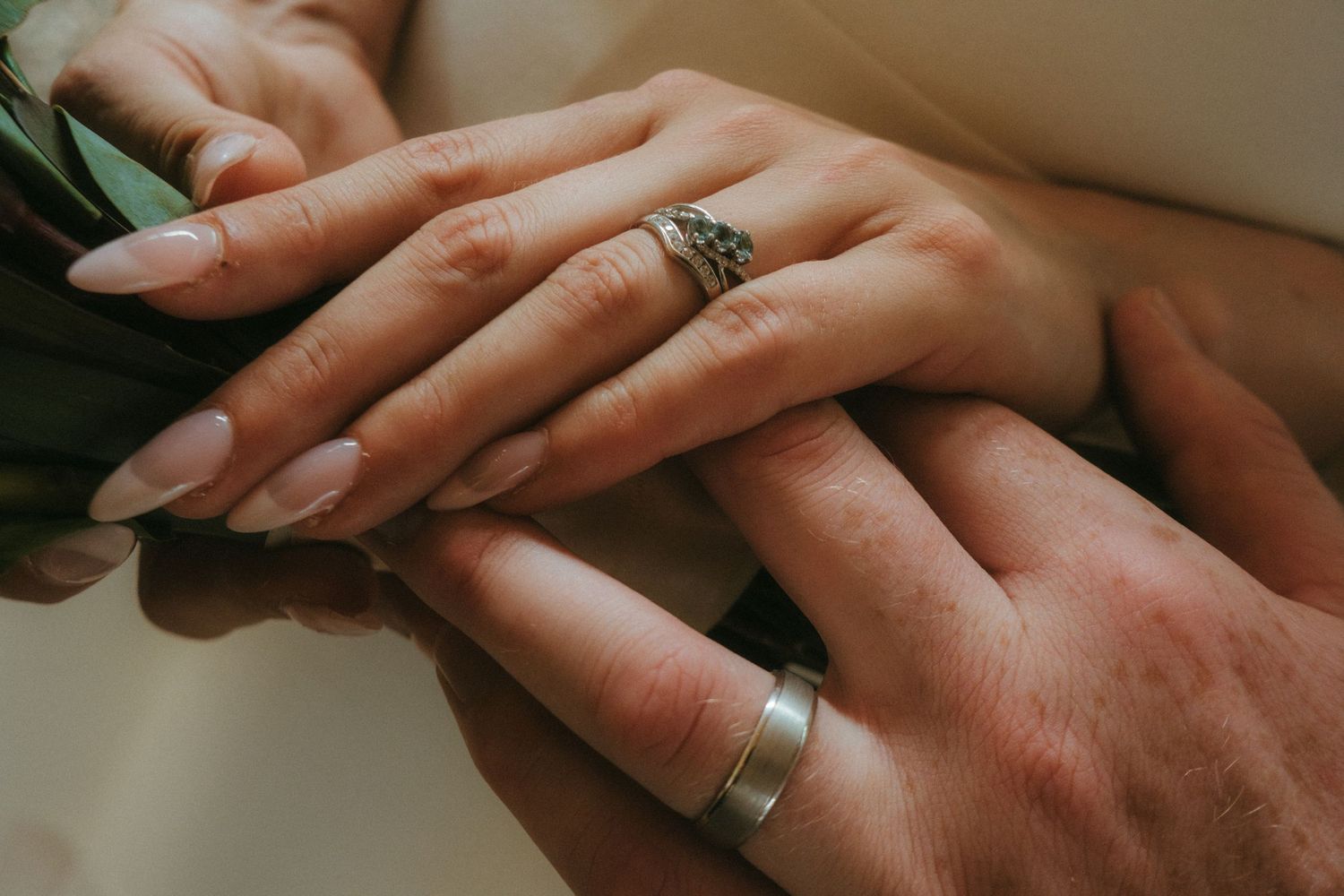 Clode up of rings while bride and groom are holding hands.