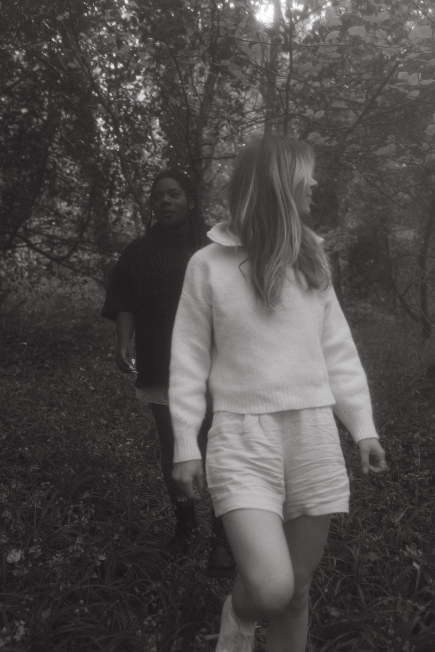 Black and white photograph of two women walking around an Irish forest in summer