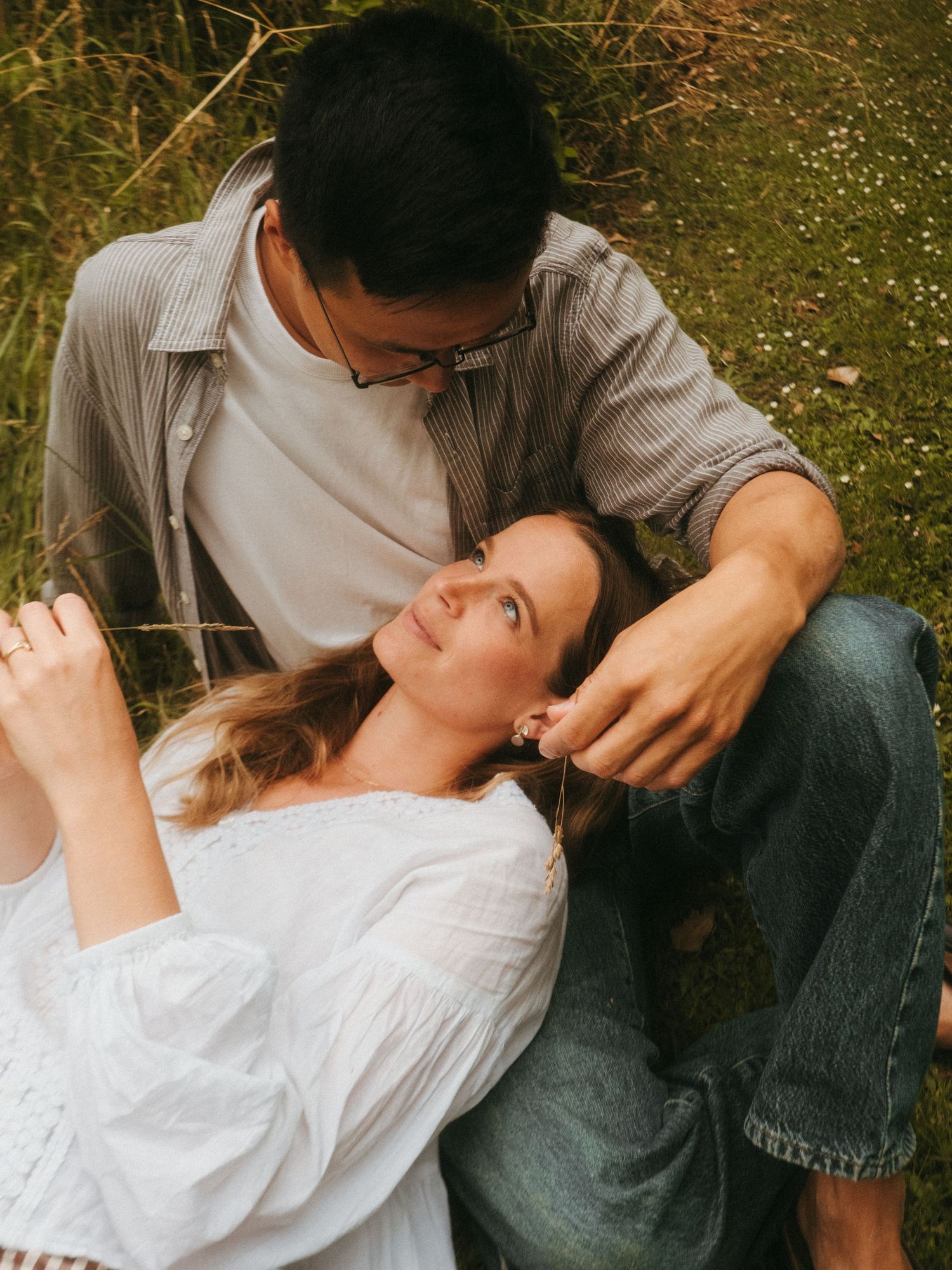 Color photograph of a woman laying in her husbands lap, he's stroking her hair