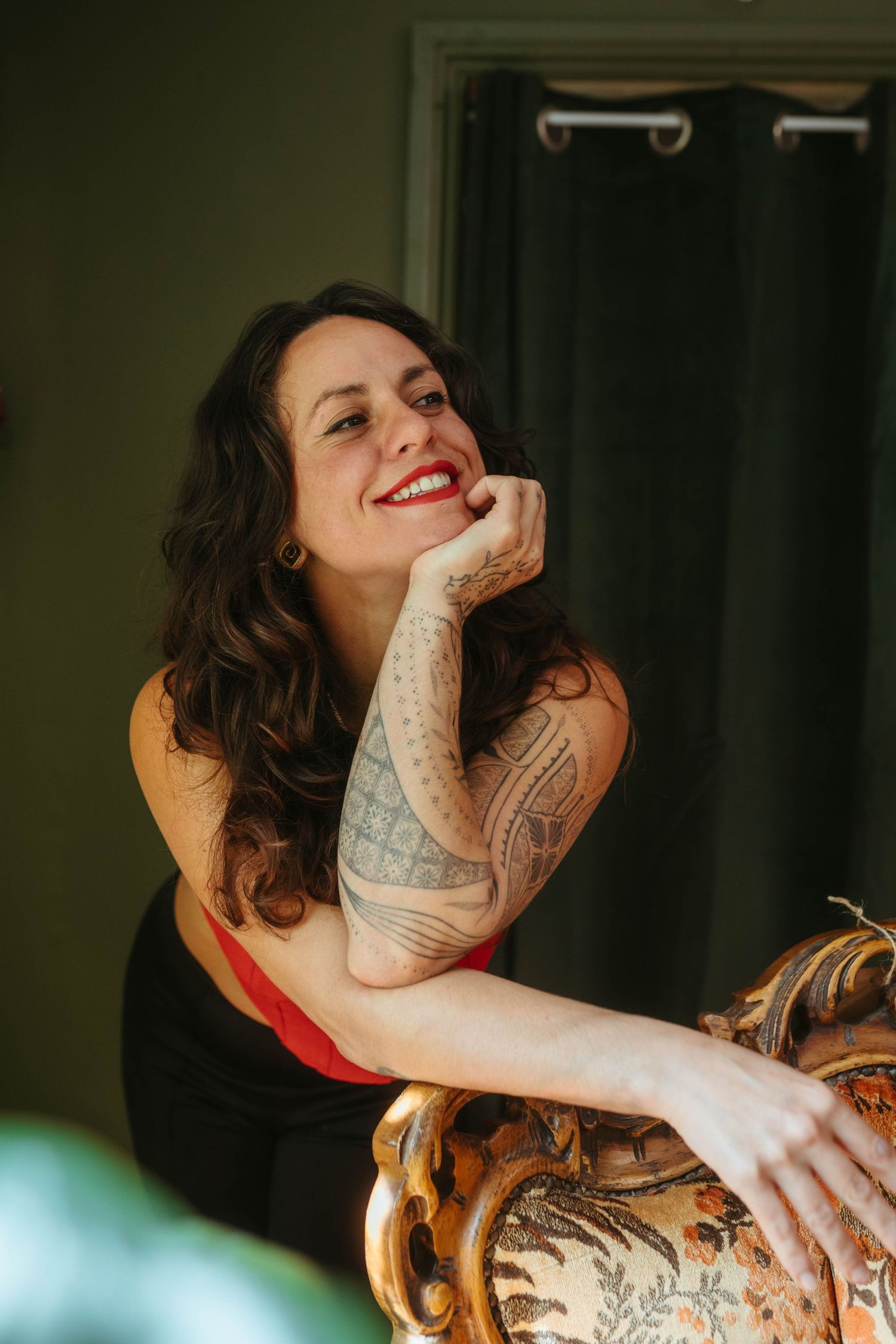 Portrait of woman with dark hair leaning against a chair