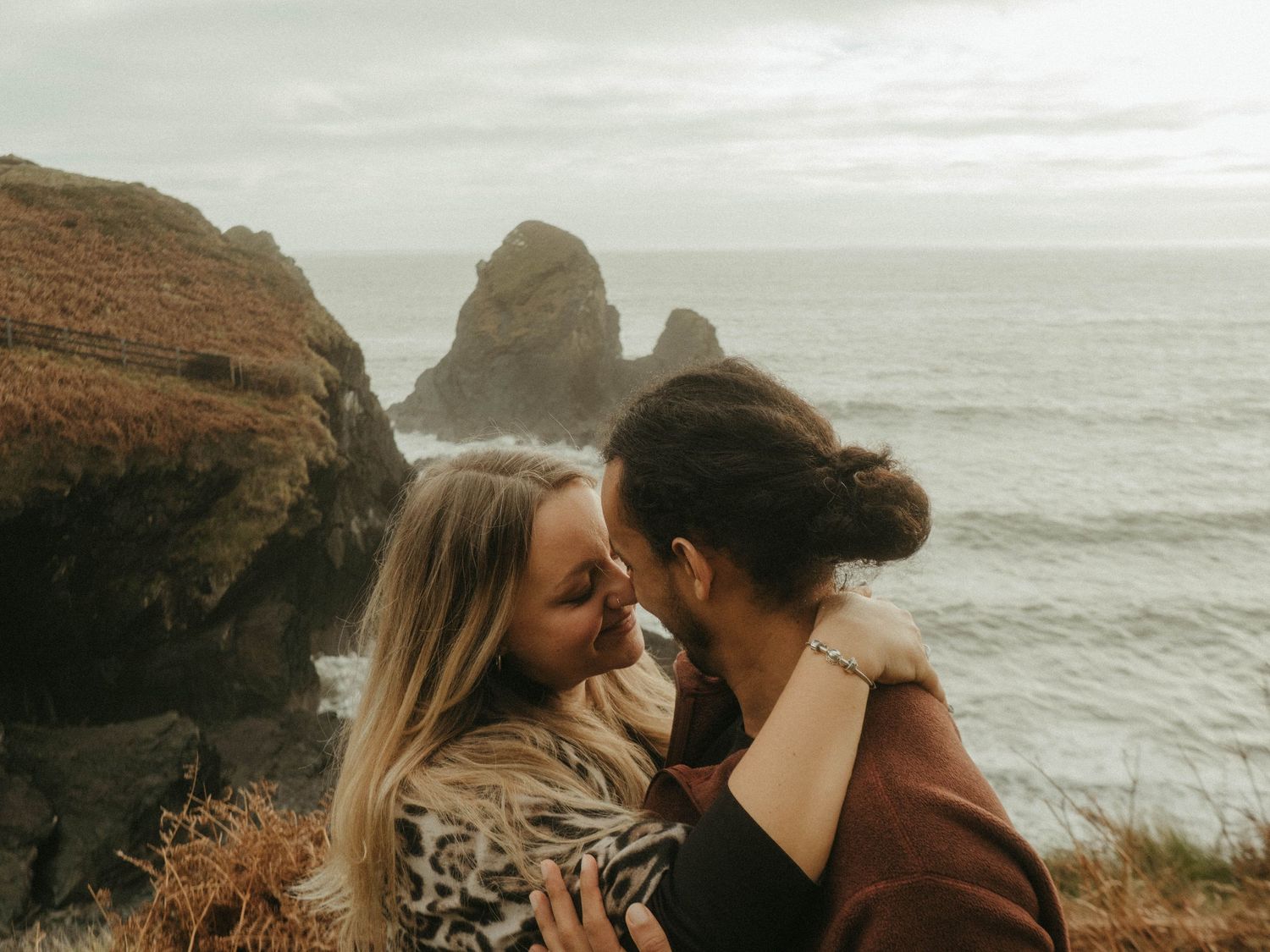 Photograph of couple posing at Nohoval Cove in Cork, Ireland. Soft contrast, warm colors.