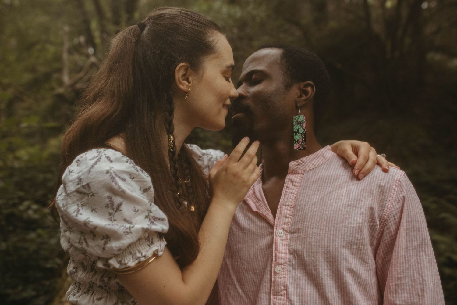 Photograph of couple almost kissing in a forest setting