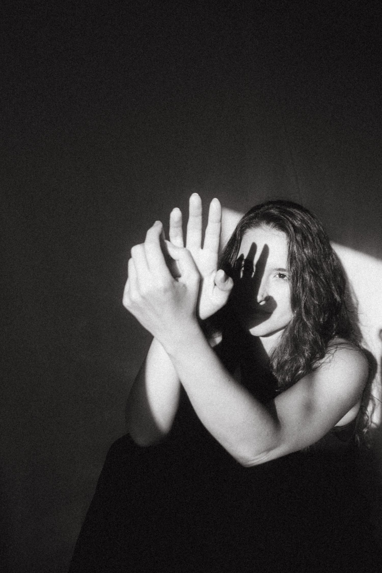 Black and white photograph of a dark haired model in a studio setting, soft contrast.