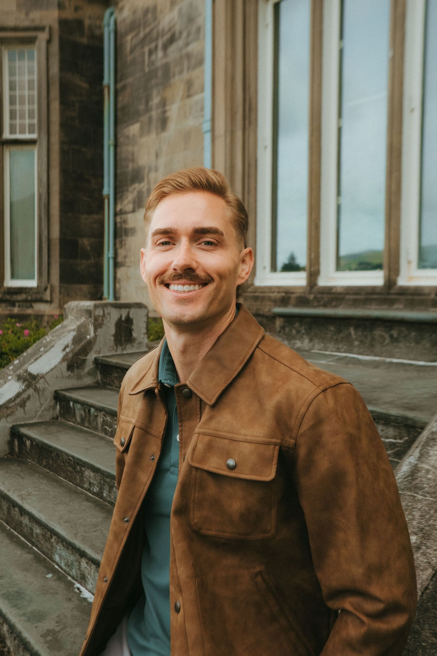 Portrait of young man in Killarney National Park, he has short blonde hair and a mustache.