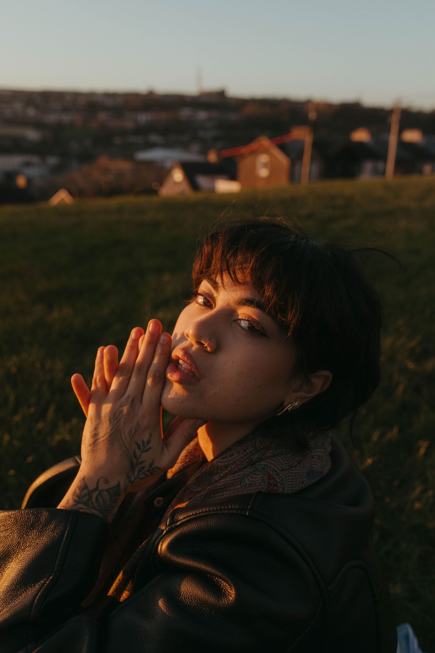 Color photograph of a young woman posing on Patricks Hill, Cork. The sun is illuminating her face, she has dark short hair