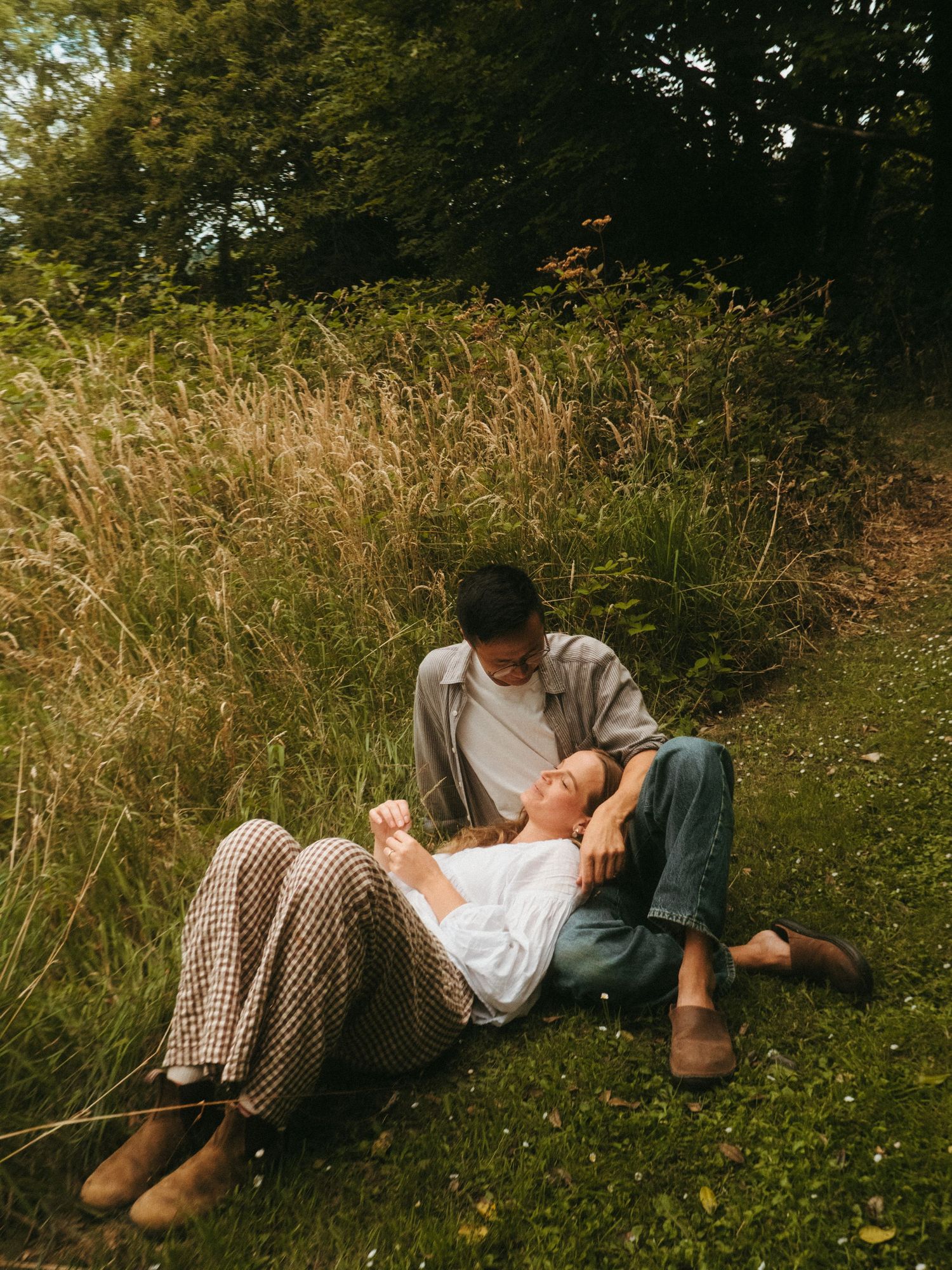 Couple resting on grass, she's laying her head in his lap - couple session