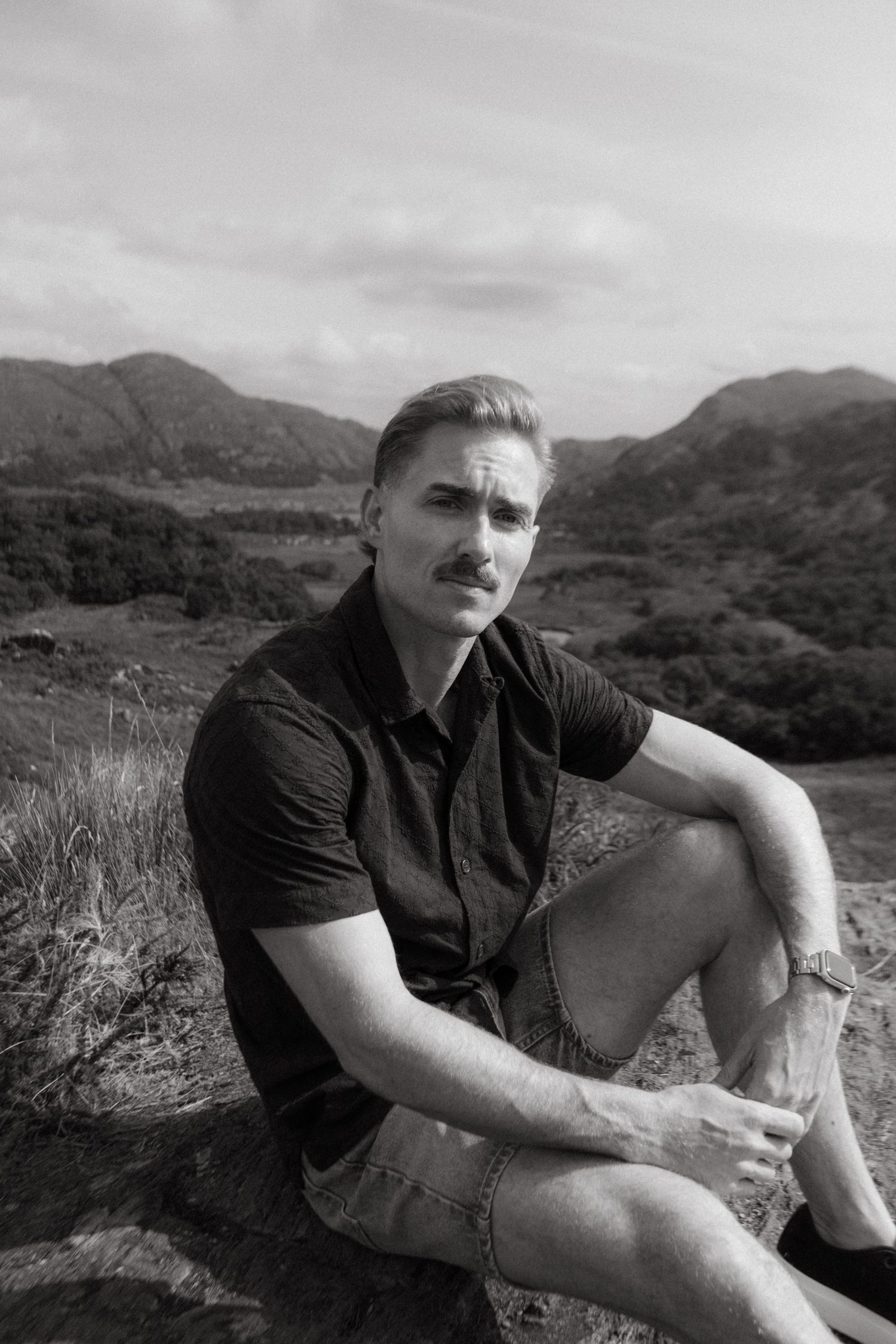 Portrait of young man in Killarney National Park, he has short blonde hair and a mustache.