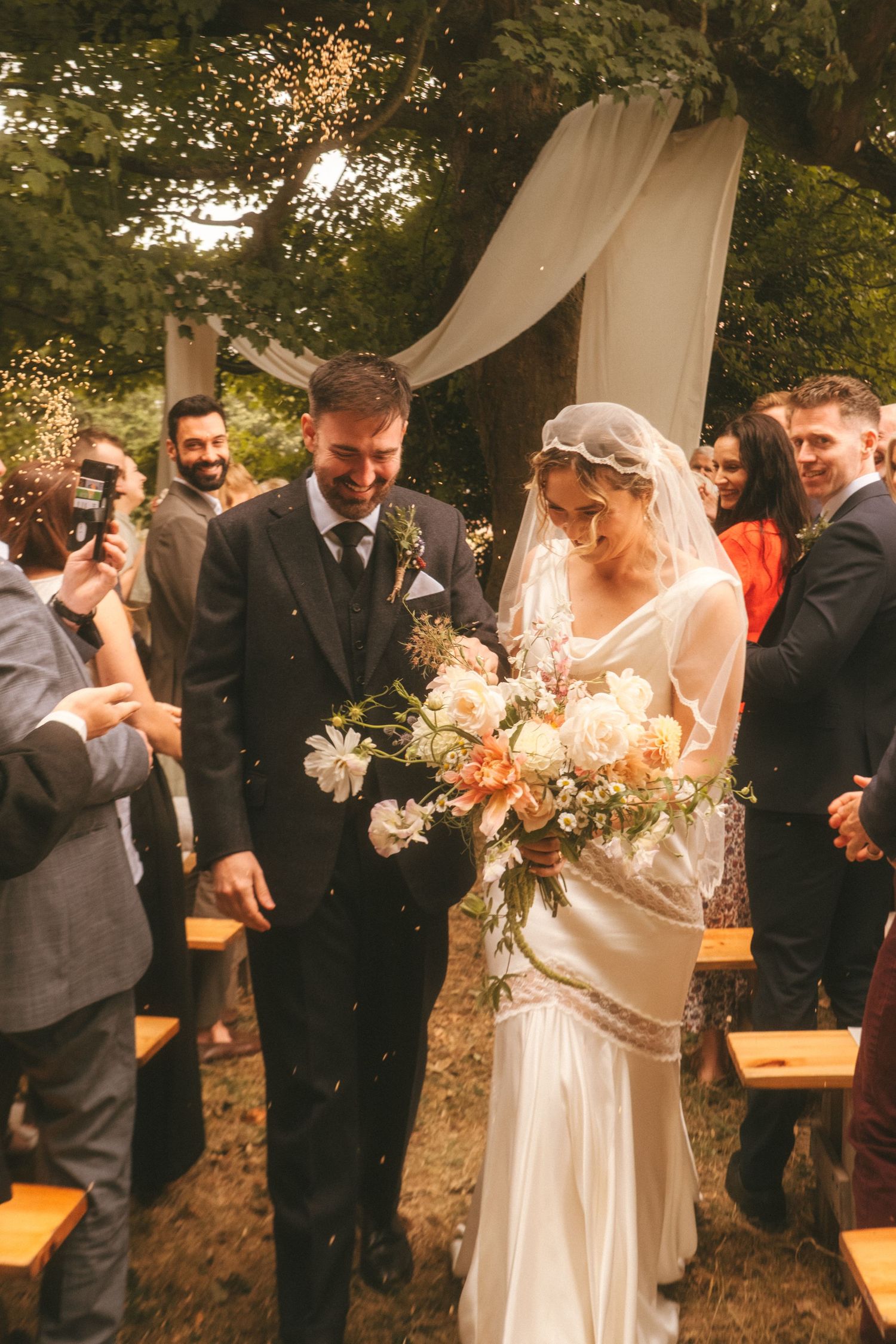Photograph of bride and groom exiting their wedding ceremony, barley is being thrown at them