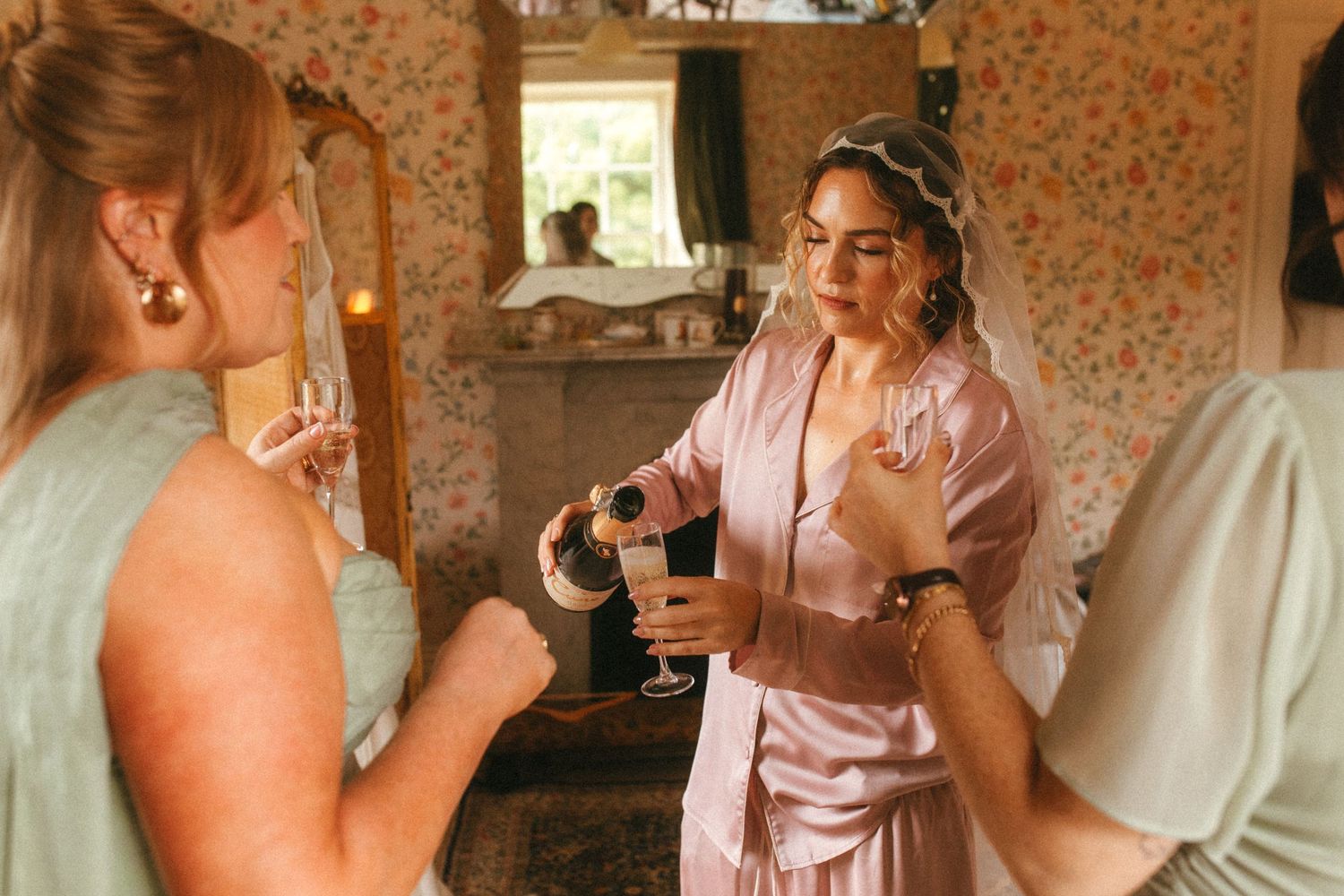 Photograph of bride and bridesmaids during the getting ready, the bride is pouring champagne