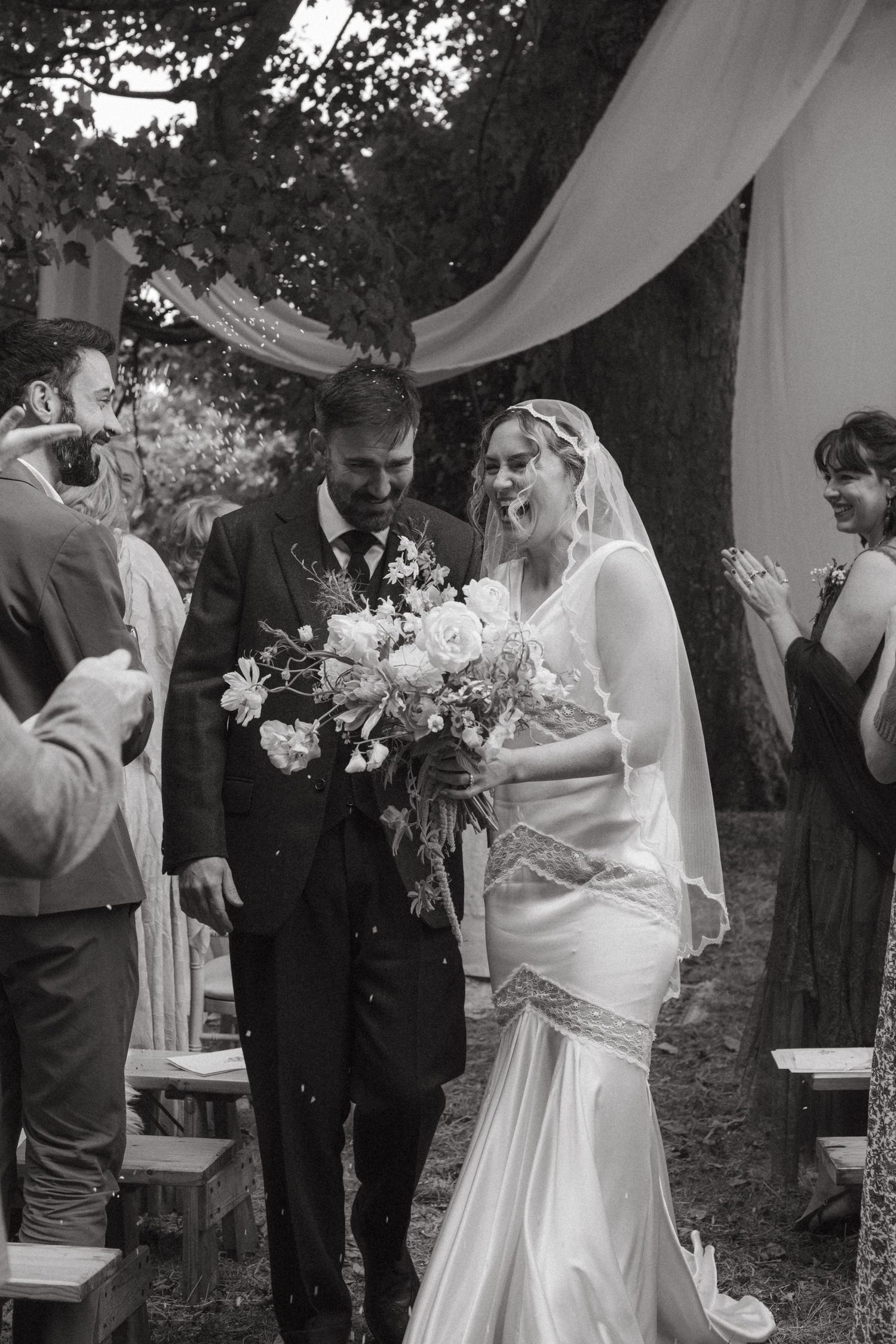 Black and white photograph of bride and groom exiting after their ceremony, barley is being thrown at them