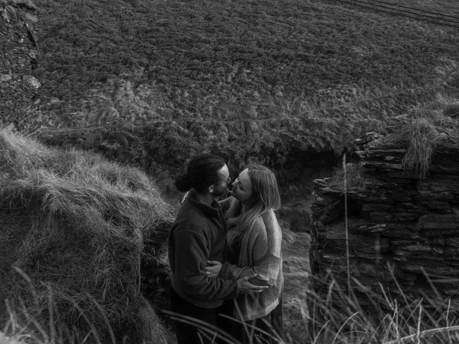 Photograph of couple posing at Nohoval Cove in Cork, Ireland. Soft contrast, warm colors.