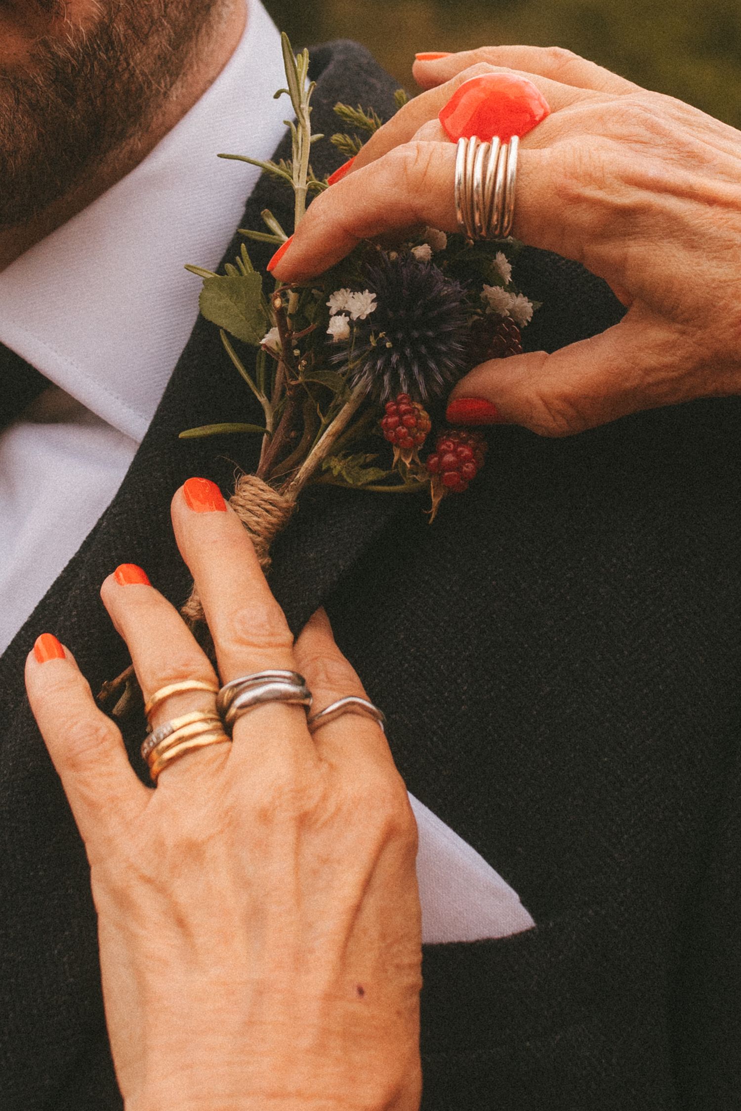 Detail shot of grooms mother fixing his flower pin