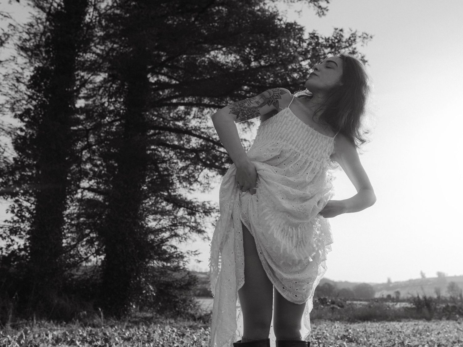 Black and white photograph of a model posing in a white dress