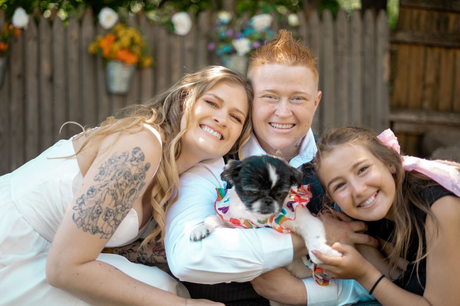 Two brides pose with their niece and dog at this backyard micro-wedding.