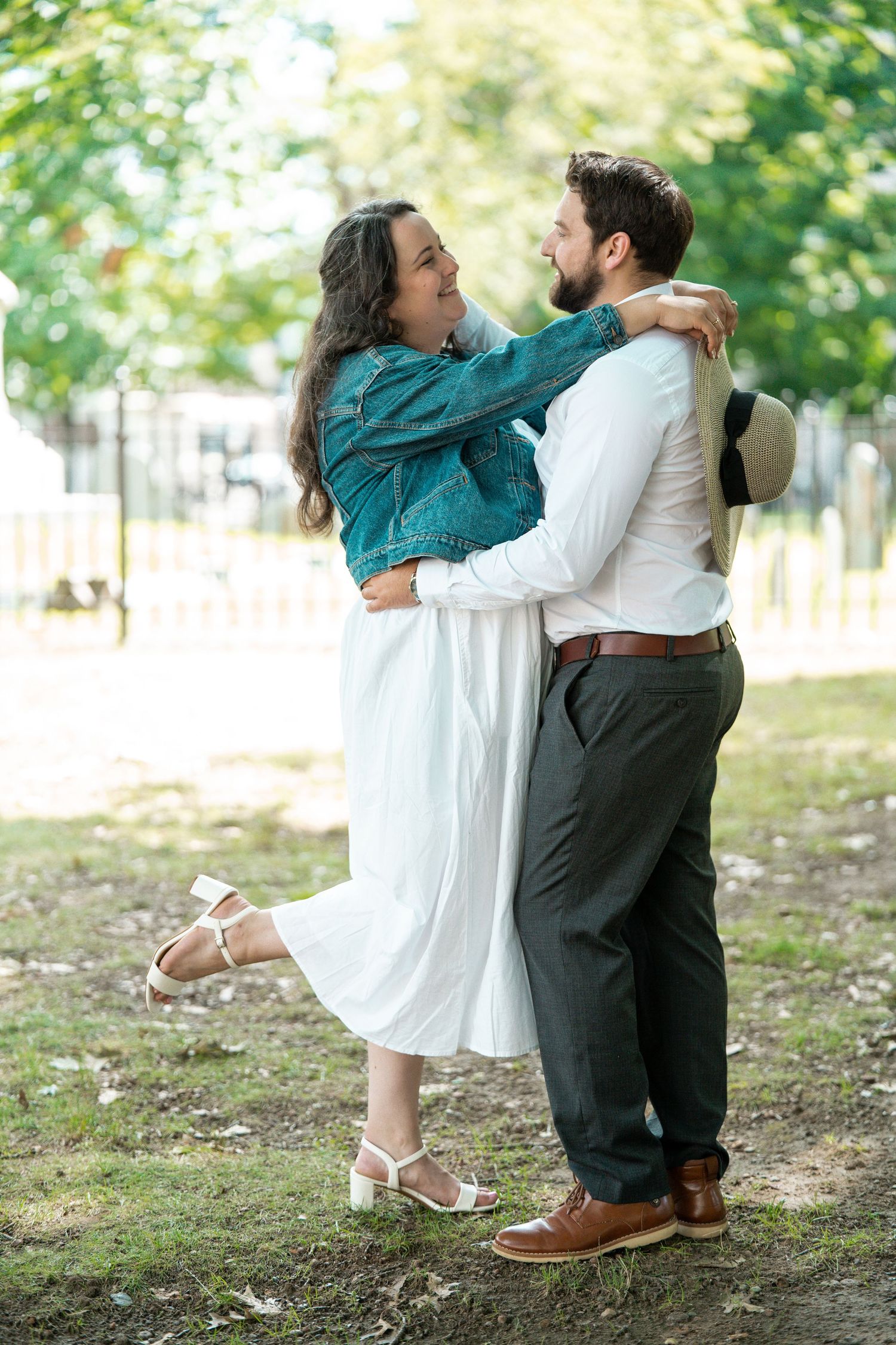 Happy couple embracing and gazing at each other in a sunny green park setting.