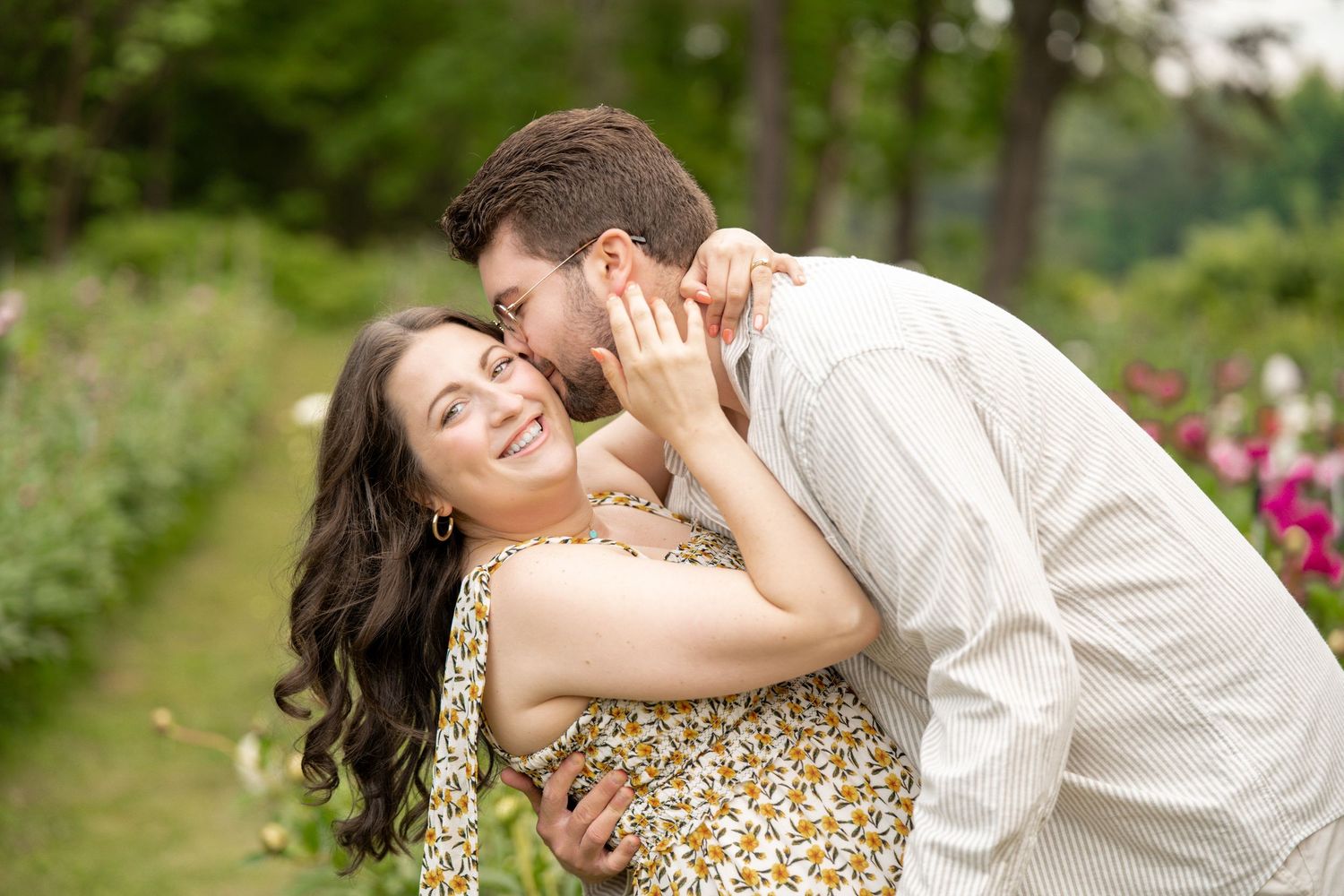 Couple sharing a tender kiss in a colorful garden during an outdoor engagement photography session.