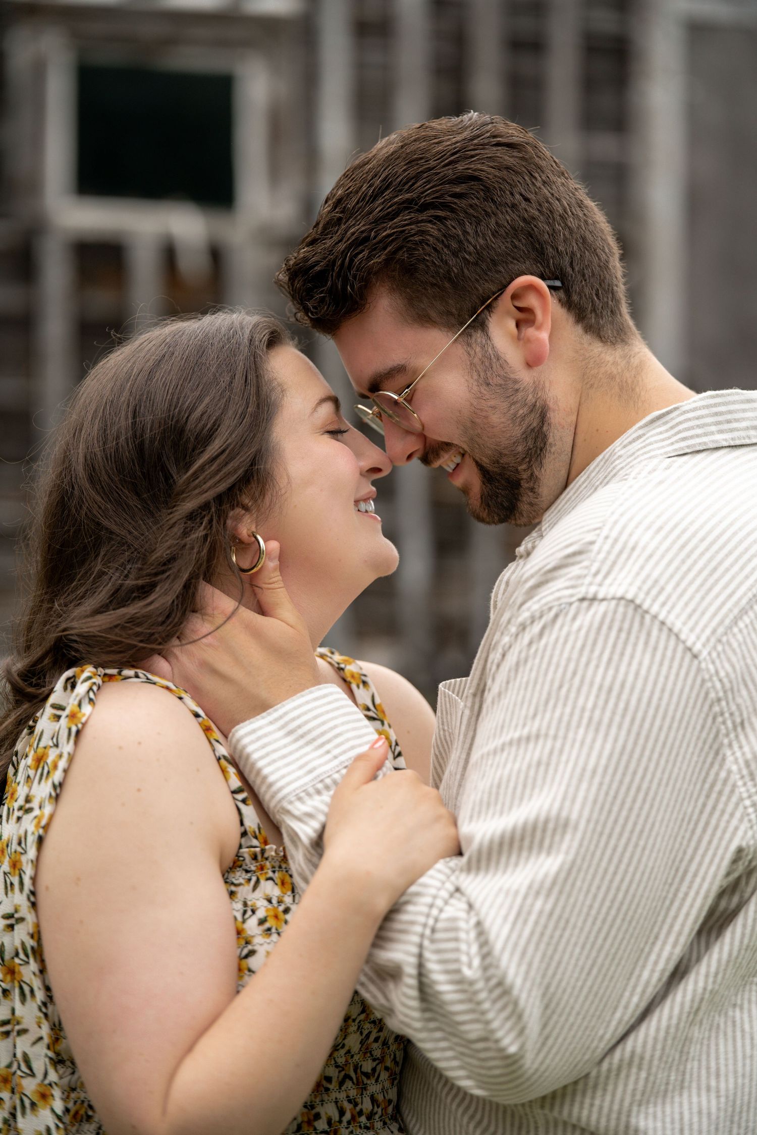Happy couple touching foreheads and smiling closely together in front of rustic wooden background.