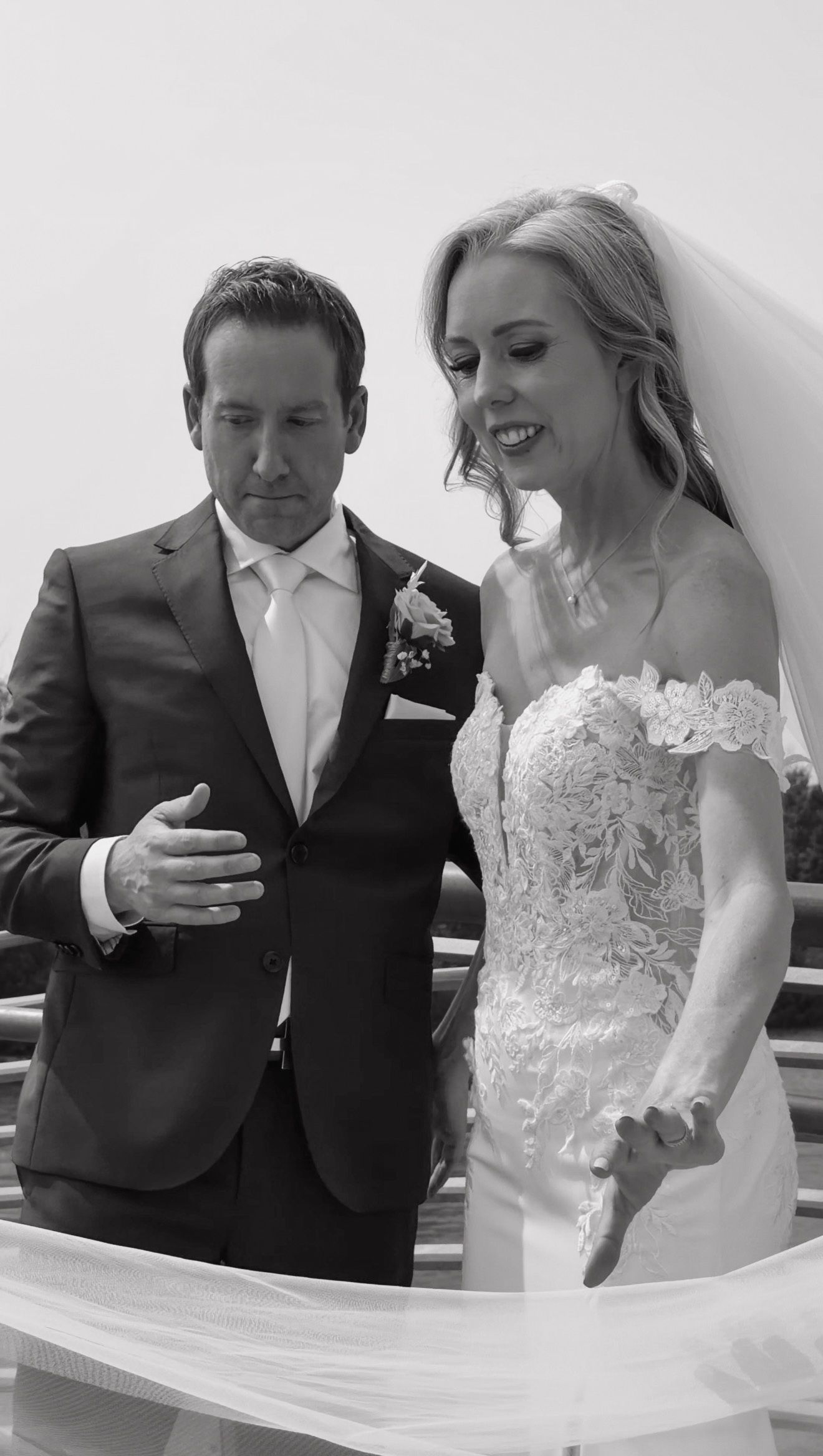 Black and white photo of bride and groom reading vows together during outdoor wedding ceremony.