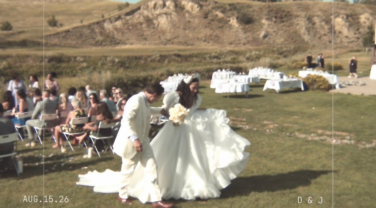 Bride and groom dance together at outdoor hillside wedding ceremony with seated guests.