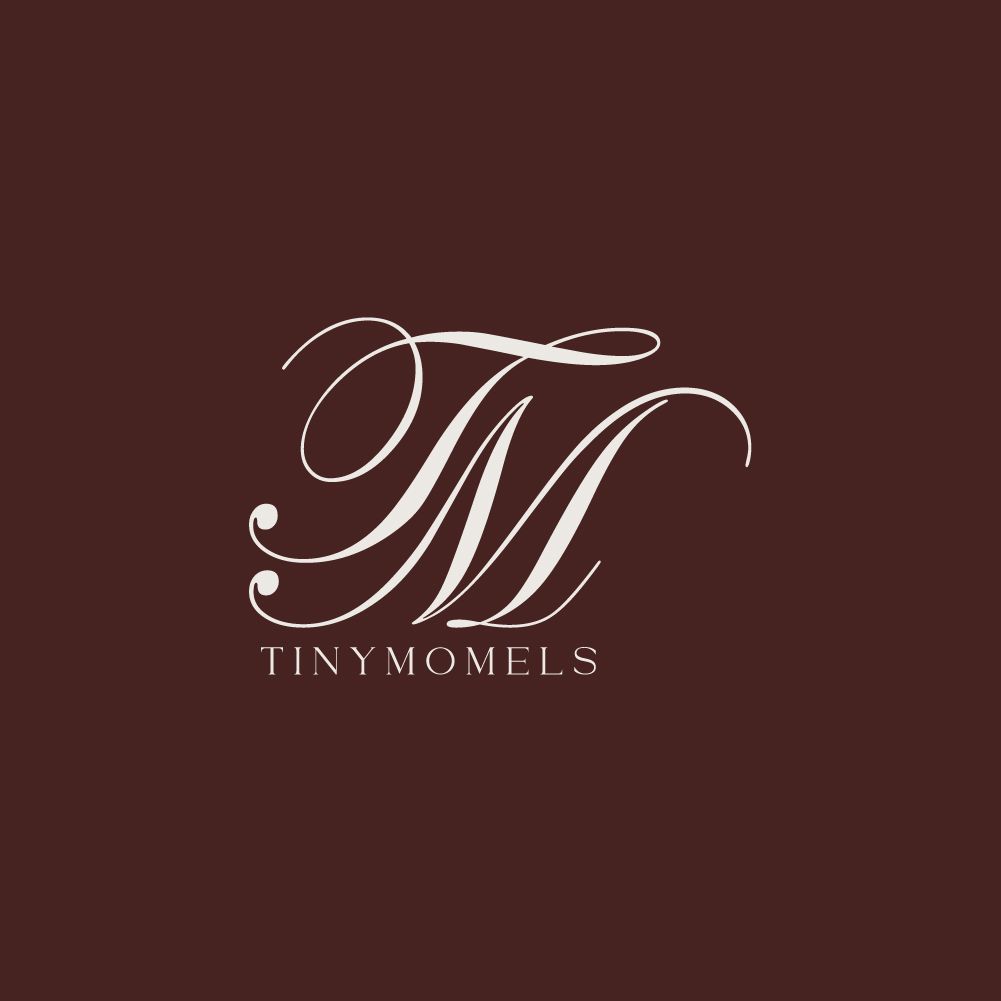 Elegant TM monogram logo for Tiny Momels in cream script on a rich dark brown background.