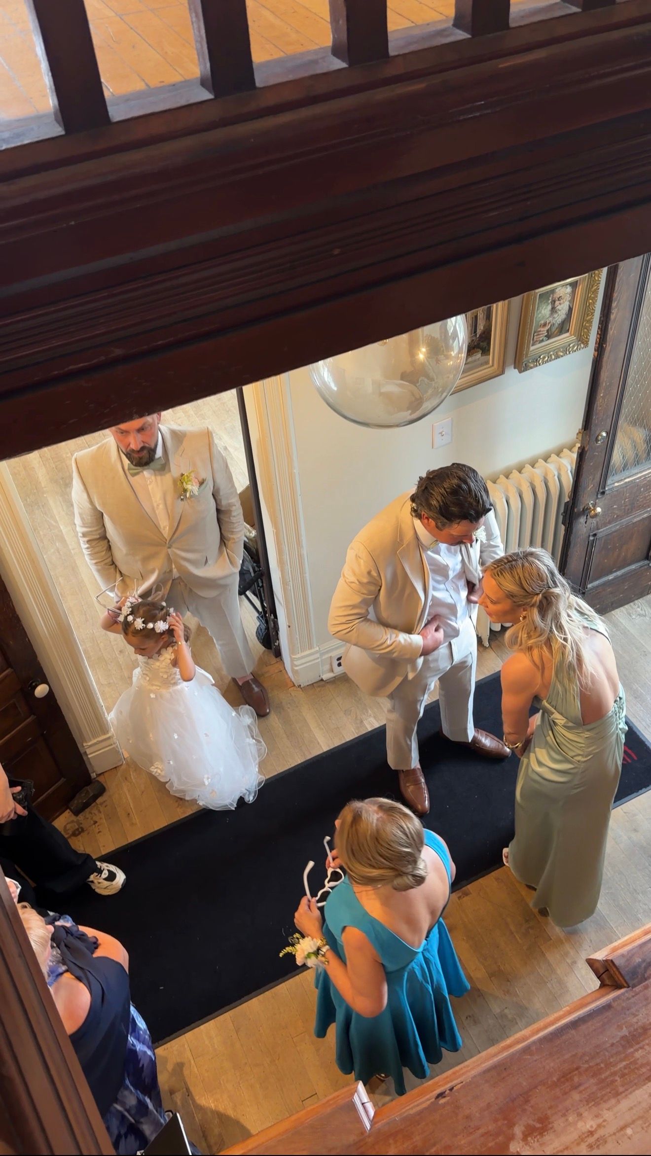 Aerial view of wedding party gathering in elegant venue foyer with bride in white gown.