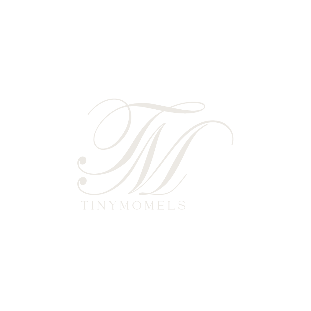 Elegant TinyMomels brand logo featuring a decorative cursive M monogram in soft white on a light background.
