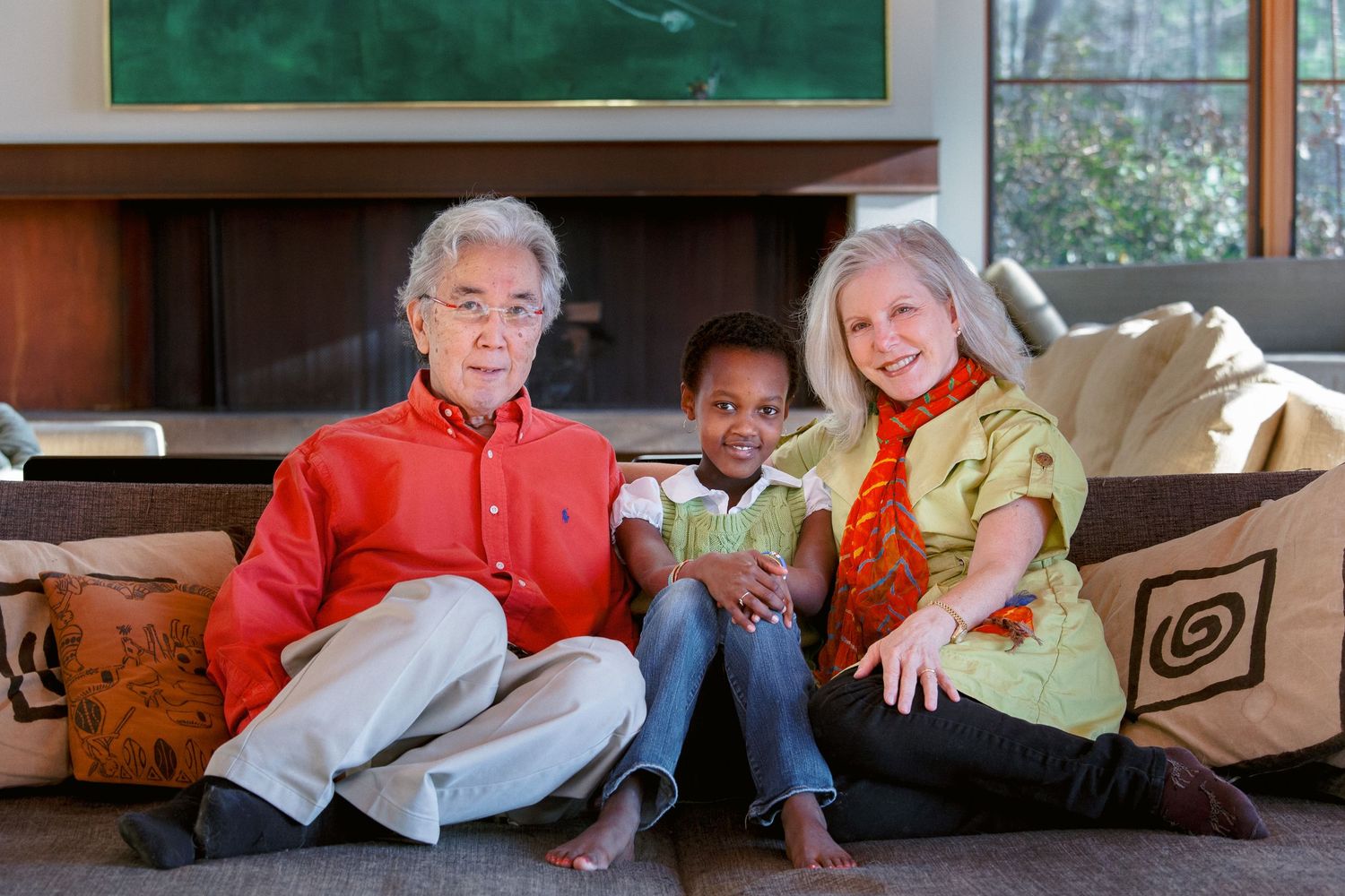 Grandparents sitting on floor with young child between them in a cozy living room.