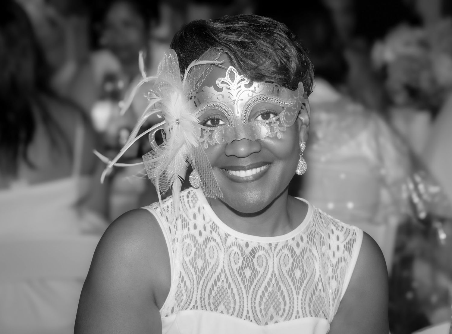 Black and white portrait of woman wearing decorative masquerade mask with feathers.