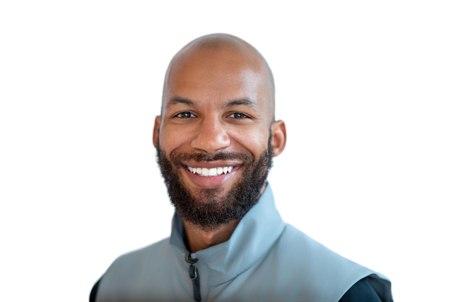 Smiling bald man with a beard wearing a teal zip-up jacket against a white background.