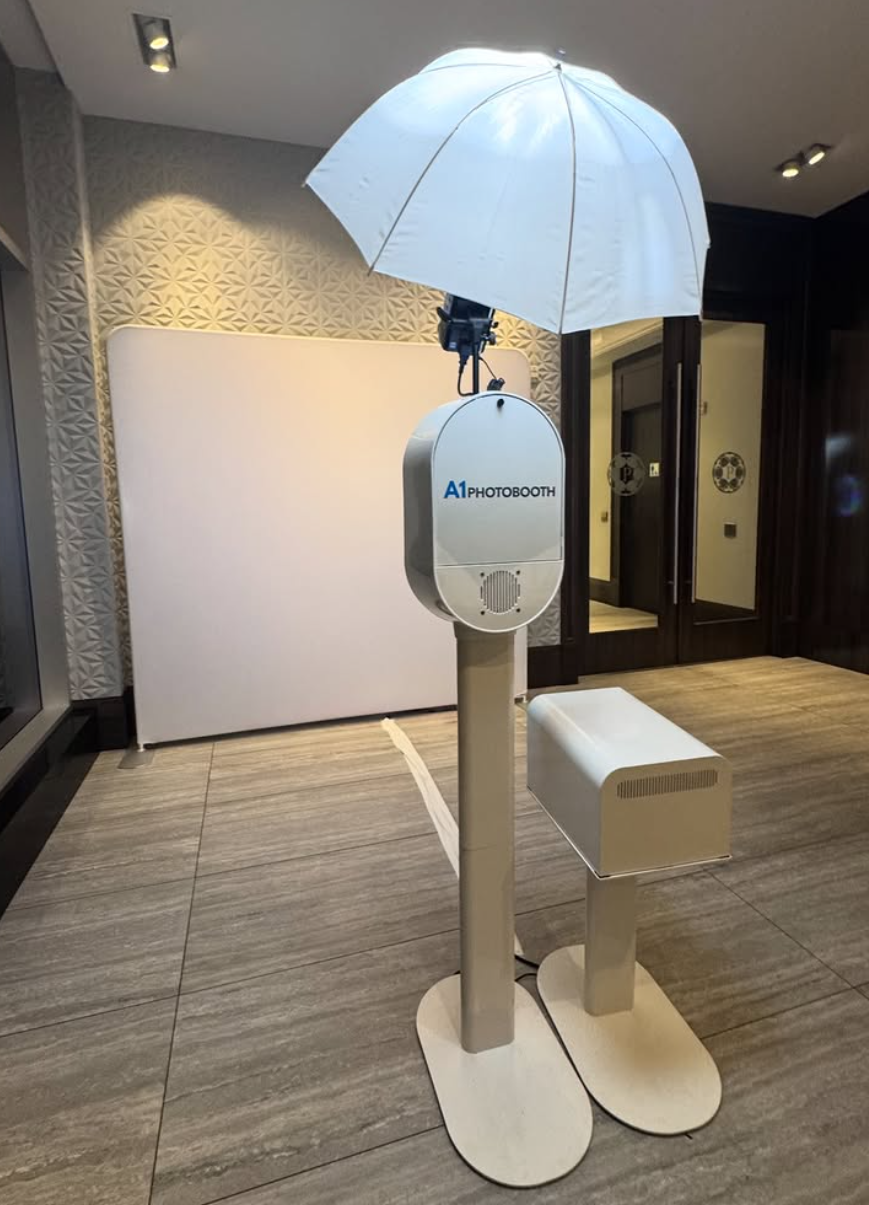 White photography studio setup with umbrella lights and reflectors arranged along a hallway with wooden flooring.