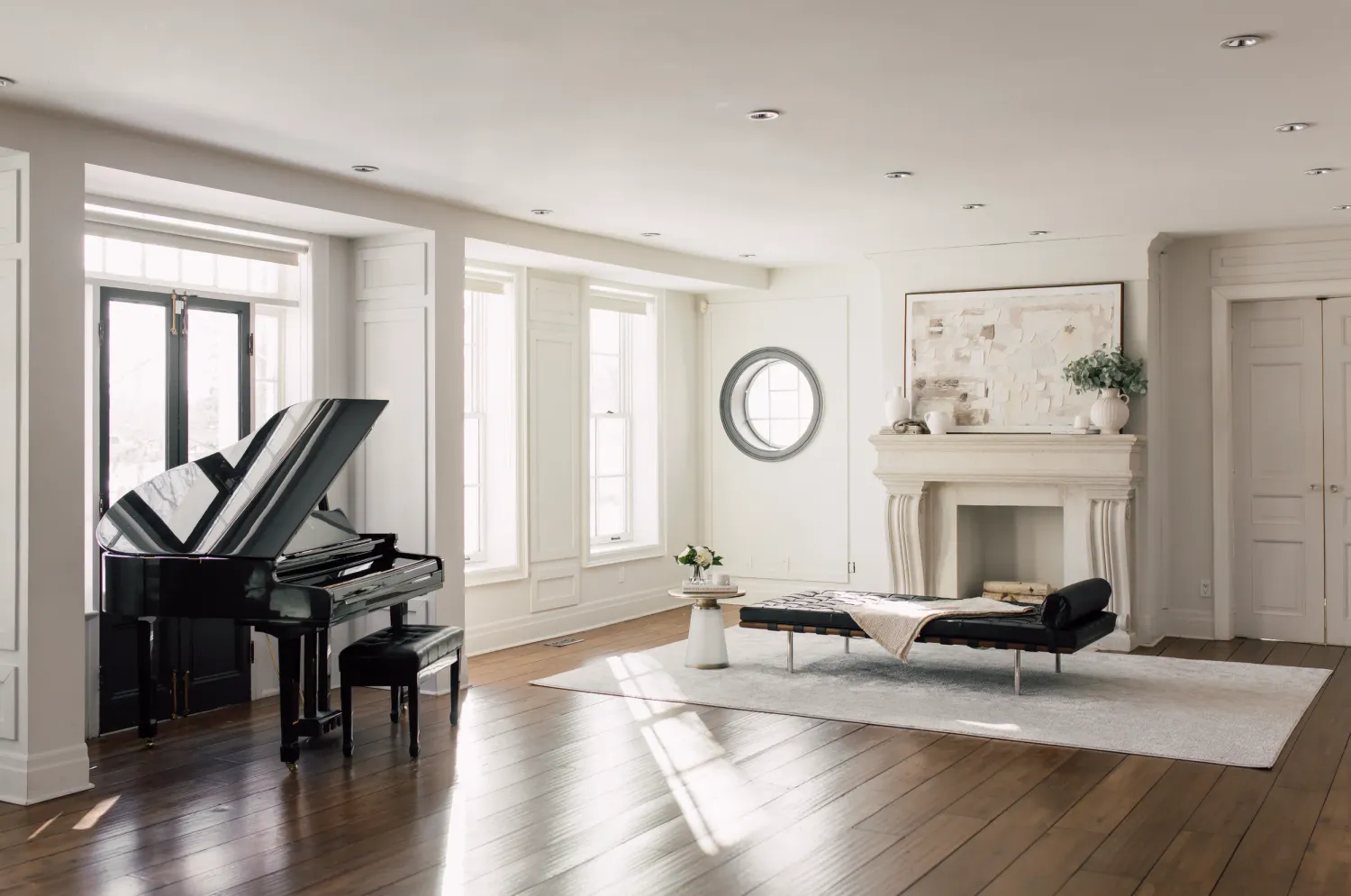 Modern minimalist white room interior with hardwood floors, grand piano, and large windows letting in natural light. Ruby Manor, Brampton