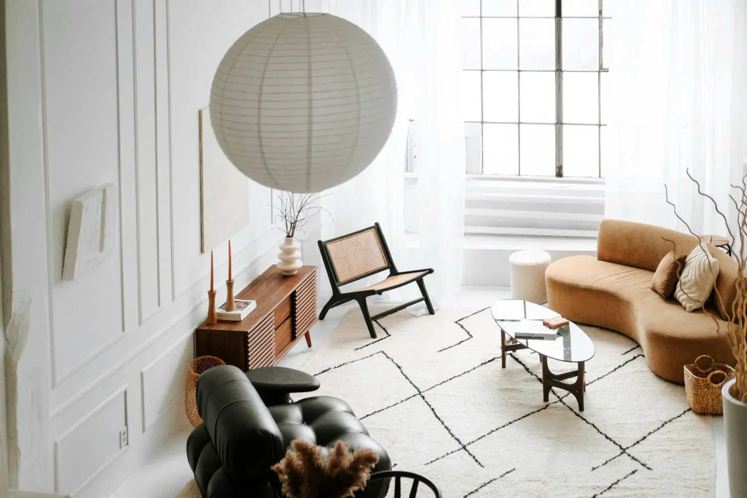Minimalist Scandinavian living room interior with white walls, paper lantern, and tan leather furniture. Nosso Studio Toronto
