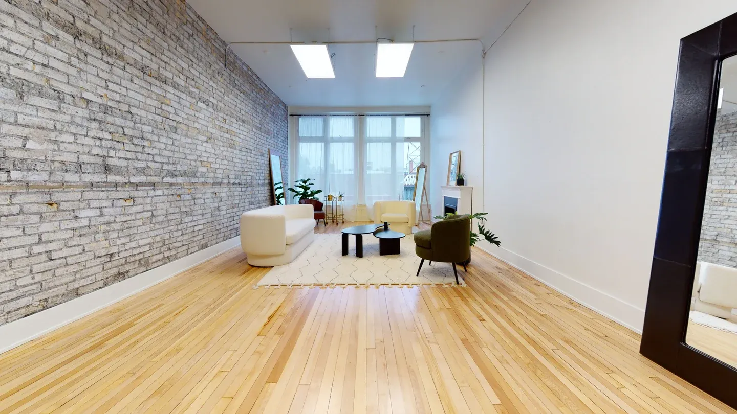 Modern yoga studio interior with exposed brick walls, hardwood floors, and bright natural lighting. West Haus Studio, Kitchener