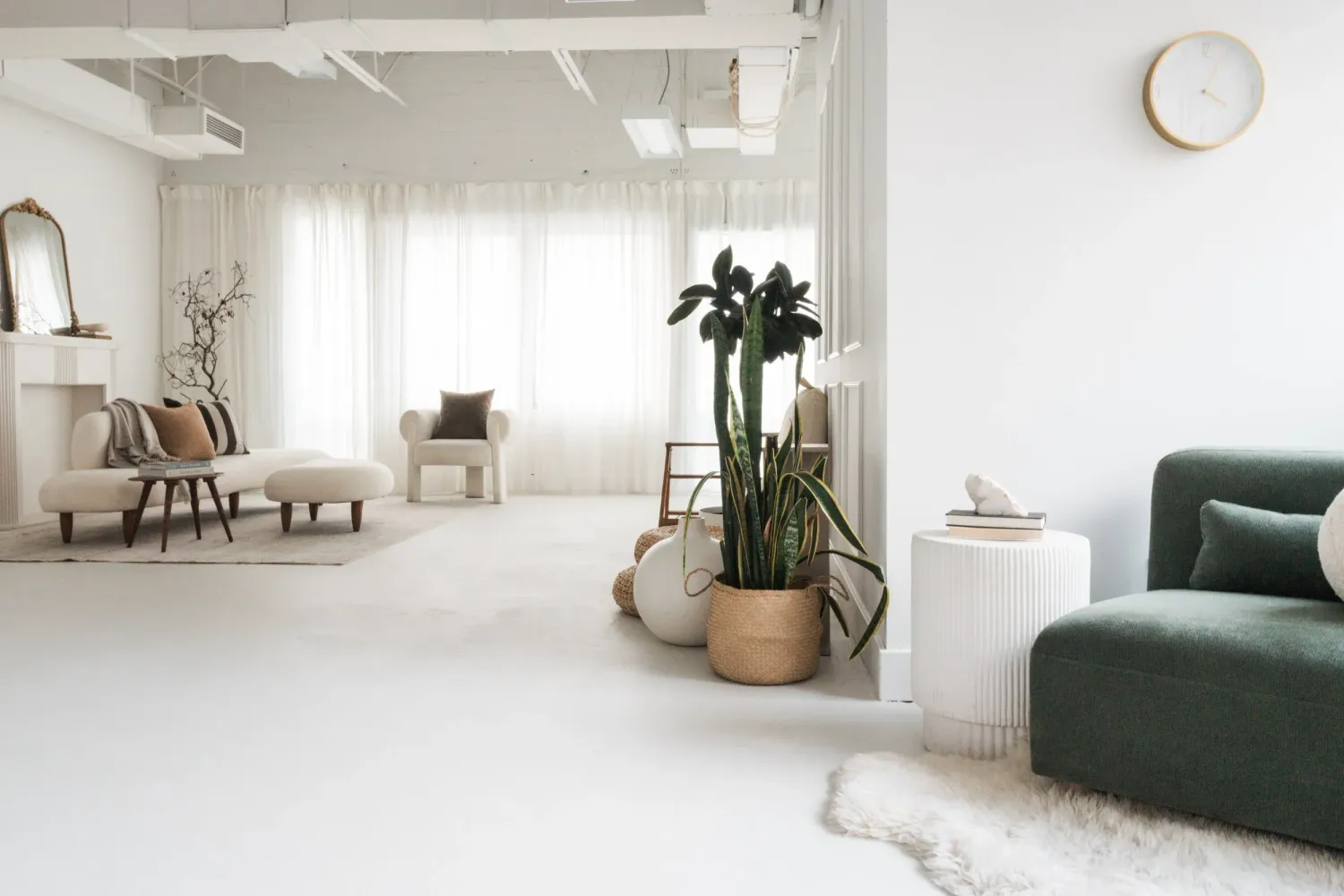 Modern minimalist living room with white walls, green accent chairs, and potted plants in a bright, airy space. The Nook Studio, Burlington
