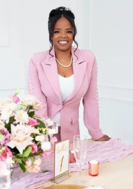Professional workspace with pink and white floral decorations on a modern desk with pink blazer accents.