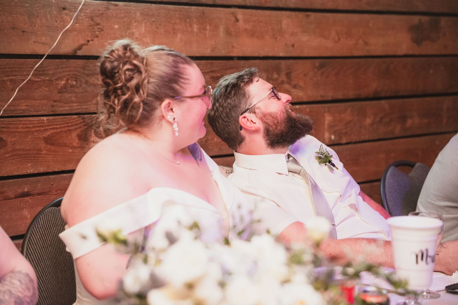 Bride and groom share a joyful moment laughing together at their rustic barn wedding reception.