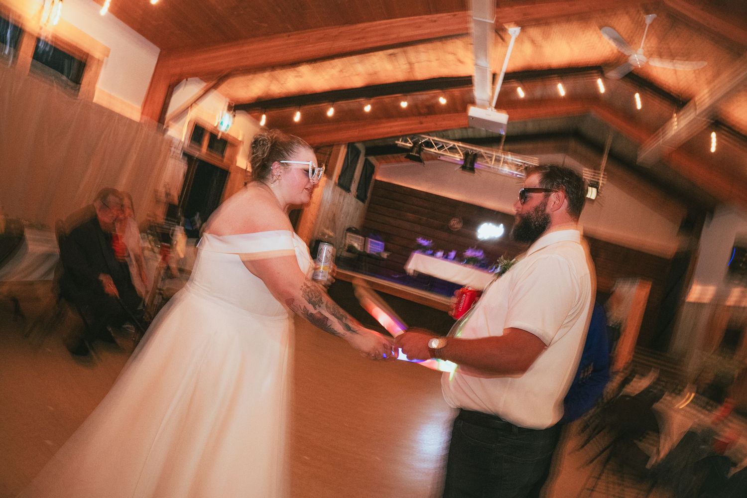 Bride and groom share a romantic first dance at their wedding reception in a warmly lit rustic venue.