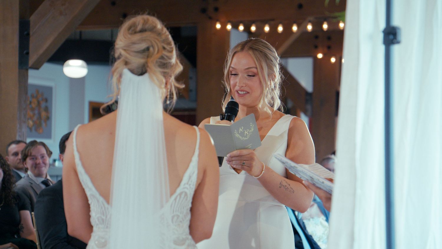 Bride reads heartfelt vows to her partner during an intimate indoor wedding ceremony.