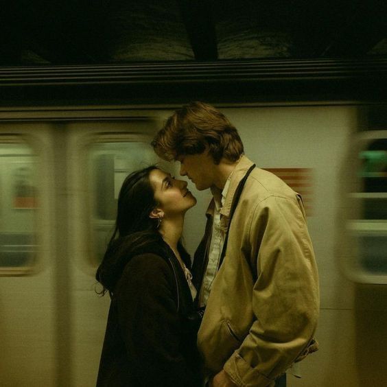 Couple sharing a romantic moment in a subway station with a blurred train passing behind them.