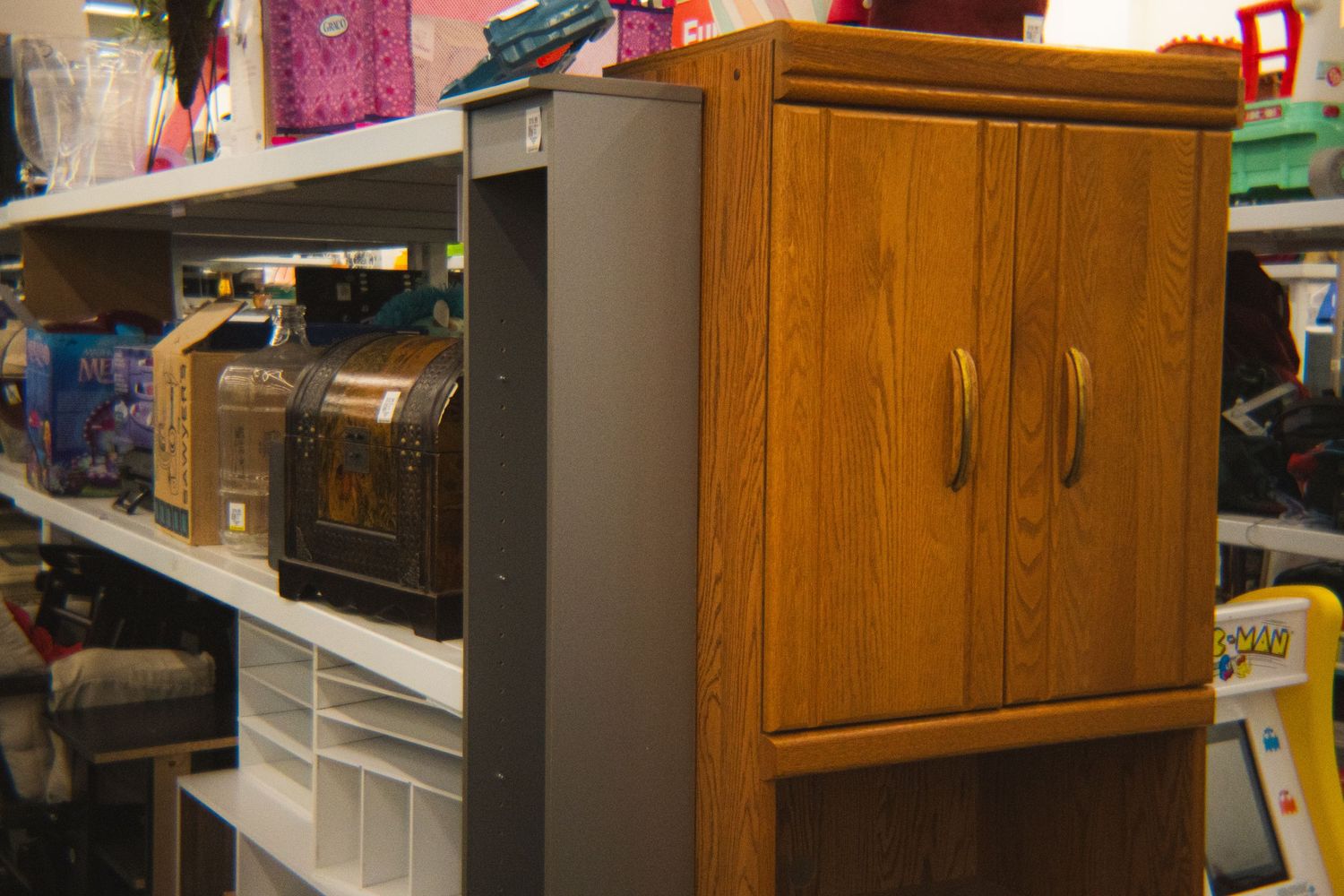 Wooden cabinet and small chests displayed on shelves in a thrift store.