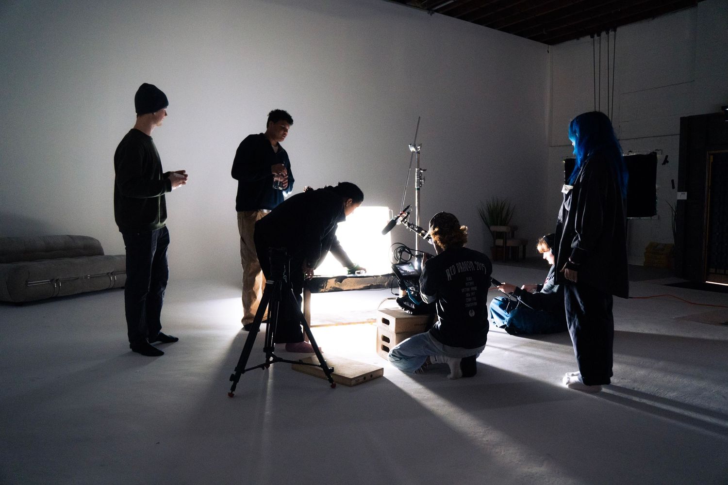 Film crew setting up professional lighting equipment in a large white studio space.