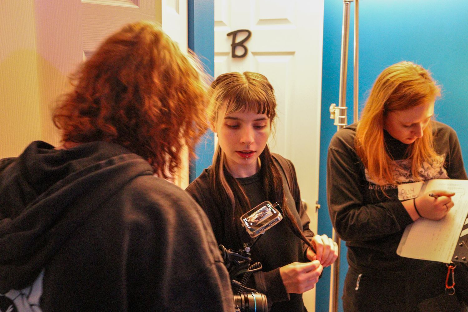 Three young filmmakers review camera equipment and notes on a film production set.