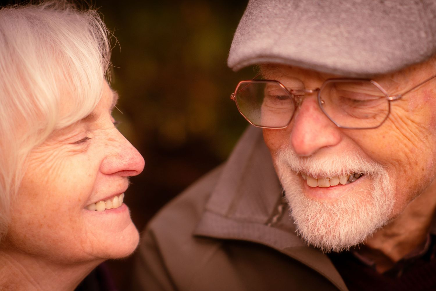 Close-up of smiling senior couple looking at each other affectionately in warm light.