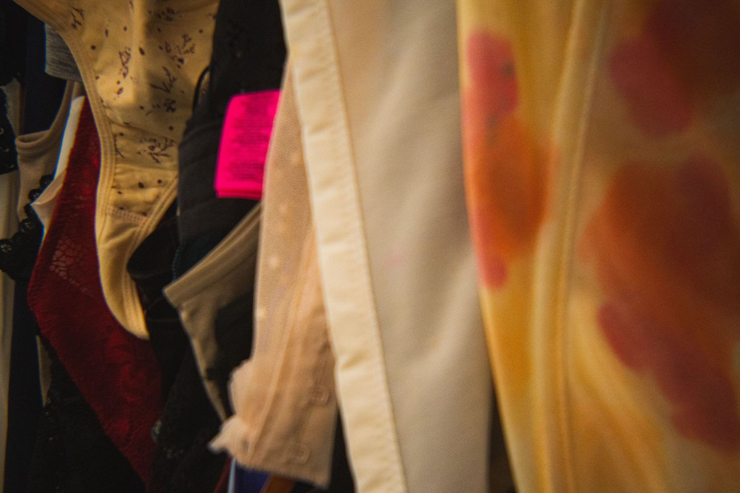 Close-up of various garments hanging on a rack in a secondhand clothing store.