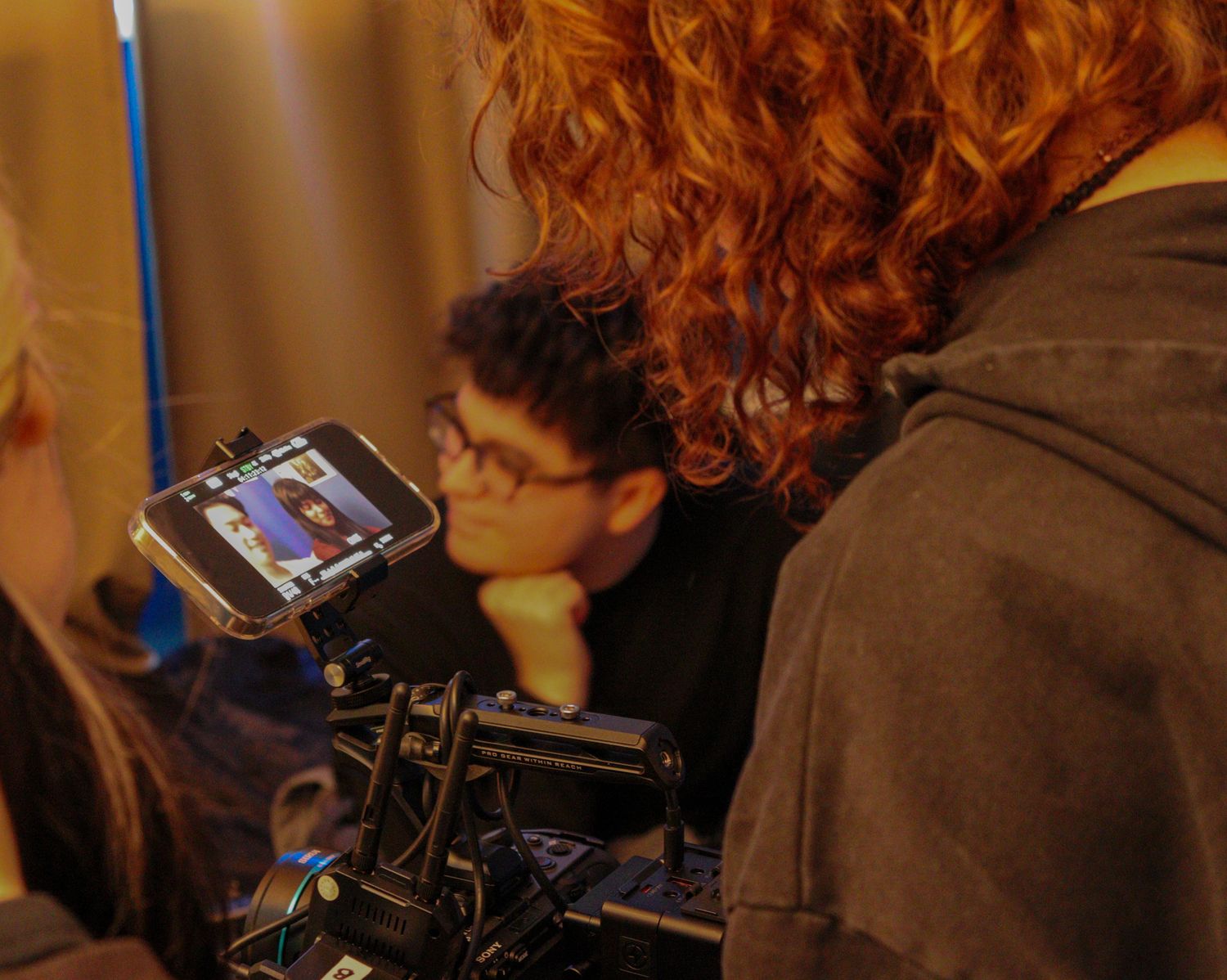 Film crew members review footage on a camera monitor during a video production shoot.