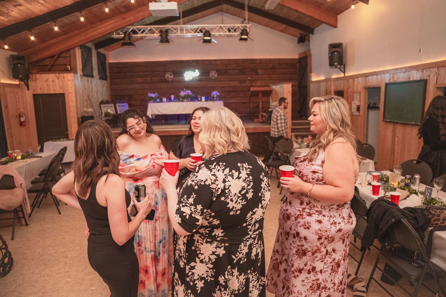 Wedding guests dancing and socializing with red cups at lively rustic barn wedding reception celebration.